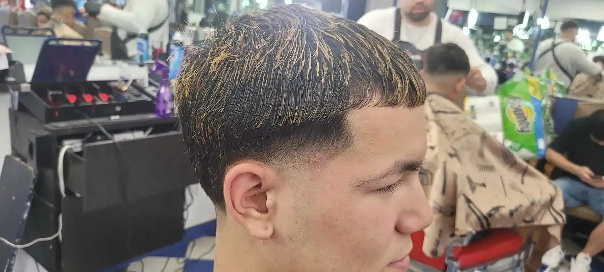 A taper fade mid cut, the shop busy behind