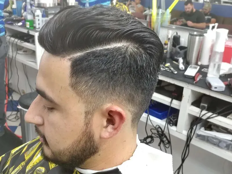 A slicked-back pompadour with a hard part and skin fade